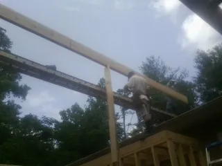 Carpenter setting a ridge beam over a new addition frame — Ice Dam Removal by Roofing Brothers in Ellston