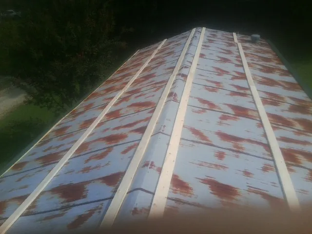 Rusted metal roof panels with new wood purlins before replacement — Storm Damage Roof Repair in Ellston by Roofing Brothers