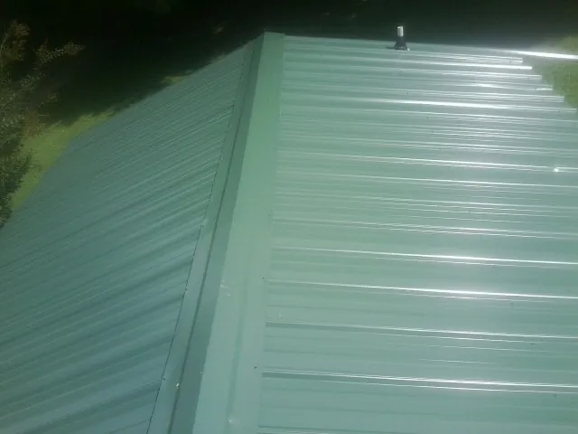 New green metal panels meeting at the ridge of a roof — Flat Roof Repair work by our crew in Ellston