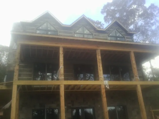 Dormers and porch framing on a large log home under construction — Roof Coating work by our crew in Ellston