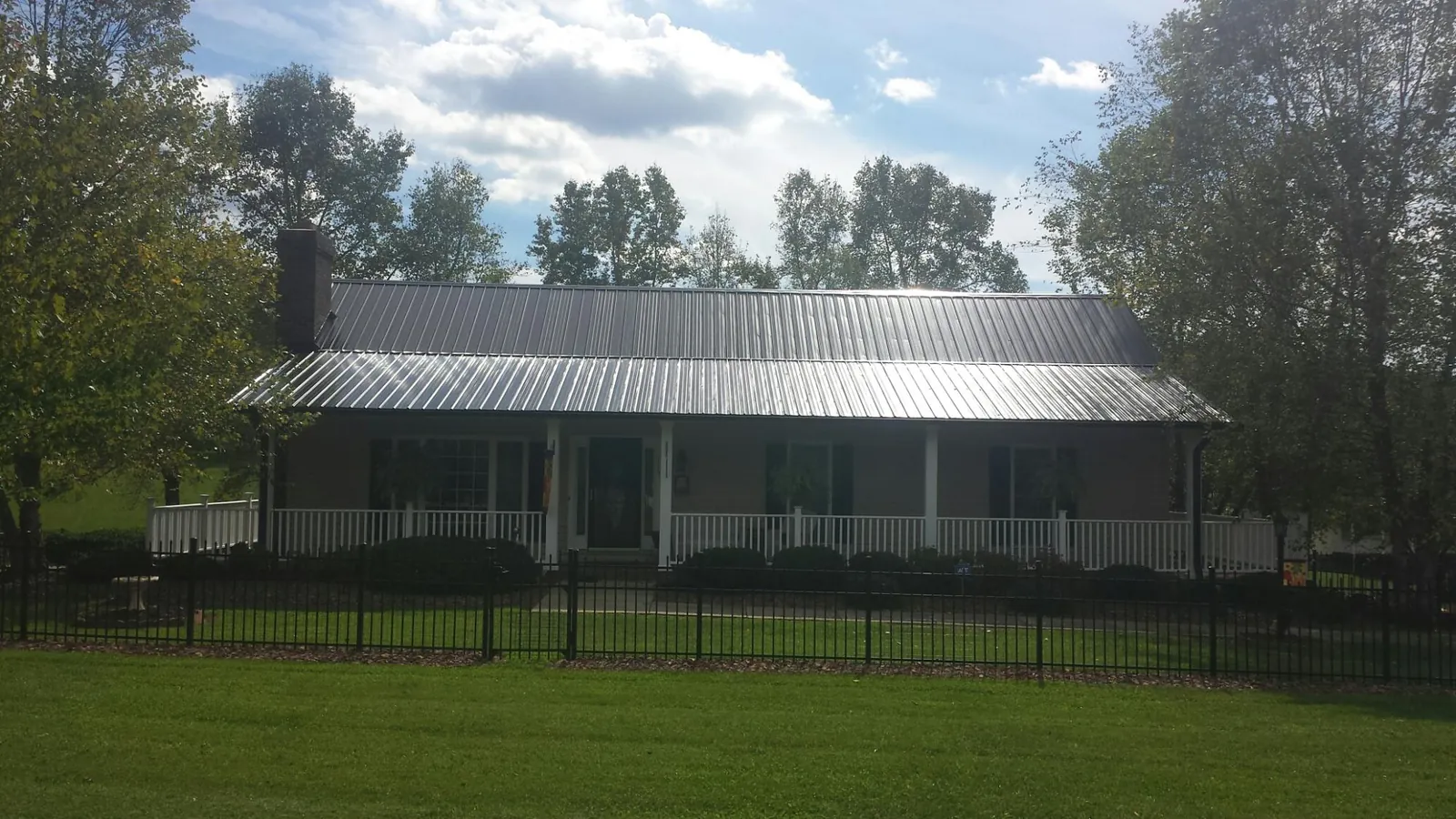 Gray metal roof on a brick ranch with a full width front porch — Gutter Guard Installation work by our crew in Ellston