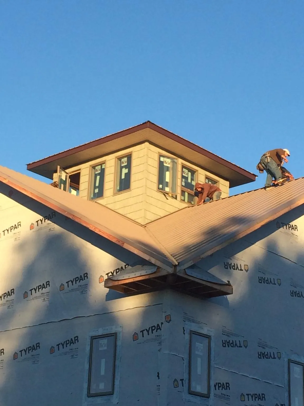 Roofers working around a rooftop cupola on a new metal roof at sunset — Roof Waterproofing in Ellston by Roofing Brothers